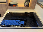 Stainless steel sink in a kitchen setting with a reflection of a blue surface.
